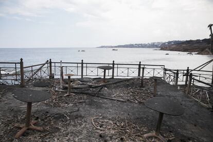 Mesas y sillas carbonizadas en una cafetería frente al mar en Mati, el 24 de julio. 