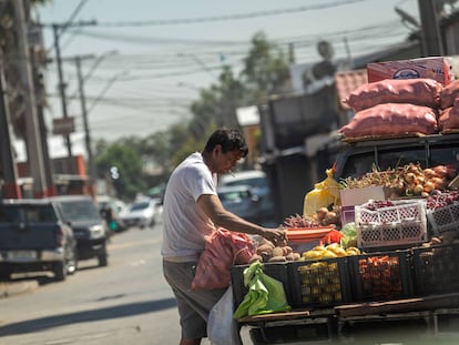 Un vendedor de frutas y verduras selecciona unas papas en su camioneta donde vende directo en los domicilios de las poblaciones de La Pintana, Chile.