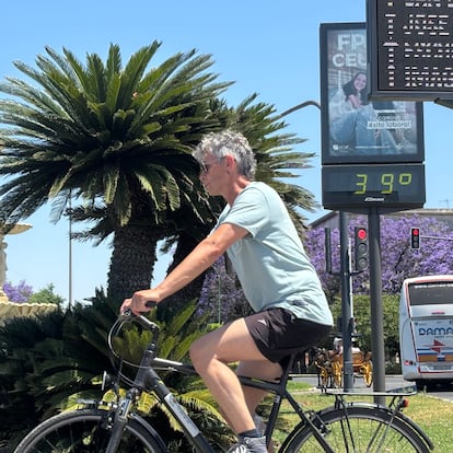 SEVILLA, 26/05/2025.- Un hombre monta en bicicleta junto a un termómetro de calle que marca 39 grados este lunes en Sevilla. EFE/Carlos Rivera