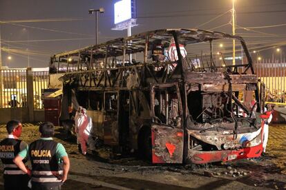 Oficiales de policía trabajan junto a los restos del autobús calcinado durante un incendio en la estación de autobuses interprovincial de Lima (Perú), que ha dejado 17 muertos y una docena de heridos.