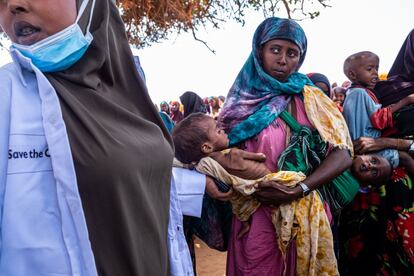 La especialista de nutrición Hawa Dakane Ahmed de la clínica móvil de Save the Children apoya a Juhara Ali (28 años) que lleva en brazos a su hija Ubah, de cuatro años, para que examinen su frágil estado de salud en el asentamiento de desplazados internos de Luglow. Su desnutrición era tan grave que a la mañana siguiente a la toma de esta foto, Ubah falleció.