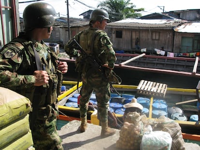 Integrantes de las fuerzas especiales del Ejército colombiano vigilan un bote que carga barriles para ser usados en laboratorios de cocaína.