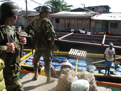 Integrantes de las fuerzas especiales del Ejército colombiano vigilan un bote que carga barriles para ser usados en laboratorios de cocaína.