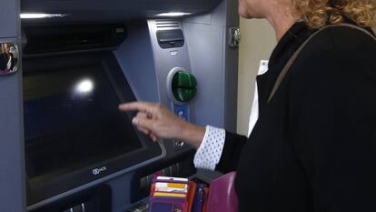 Una persona saca dinero de un cajero del Banco Sabadell.