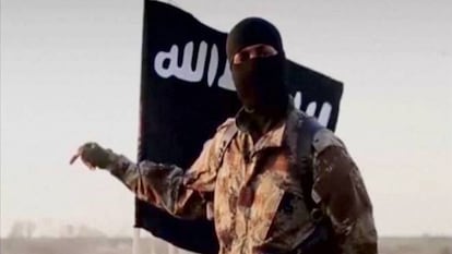 Un yihadista delante de la bandera del Estado Isl&aacute;mico (ISIS)