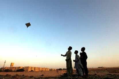Un niño y sus amigos vuelan una cometa a lo largo del lecho seco del río Lyari, en Karachi (Pakistán).