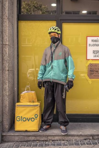 Muchos 'riders' visten prendas y mochilas de diversas marcas de reparto a domicilio. En esta imagen, Carlos, un ciclista venezolano, tras recoger un pedido a la puerta de un almacén de Glovo.