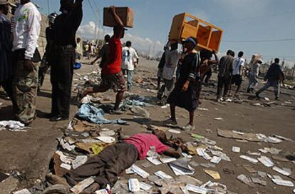 Un grupo de saqueadores pasa ante el cadáver de un hombre que intentaba robar, ayer en Puerto Príncipe.