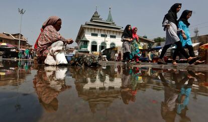 Niñas reflejadas en el agua de un charco mientras caminan por Srinagar, en Cachemira, noroeste de India, el 14 de septiembre de 2020.