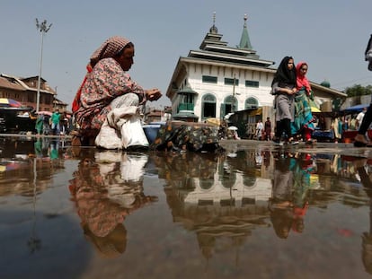 Niñas reflejadas en el agua de un charco mientras caminan por Srinagar, en Cachemira, noroeste de India, el 14 de septiembre de 2020.