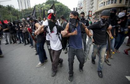 Grupo mascarado faz cordão humano durante ato contra a Copa, em São Paulo.