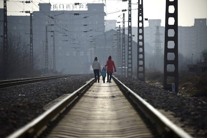 Dos mujeres y un niño caminan por unas vías de ferrocarril en Pekín (China).