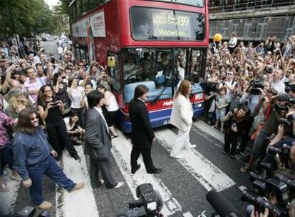 Cuatro imitadores de los Beatles cruzan el paso de cebra de Abbey Road en Londres rodeados de seguidores del grupo.