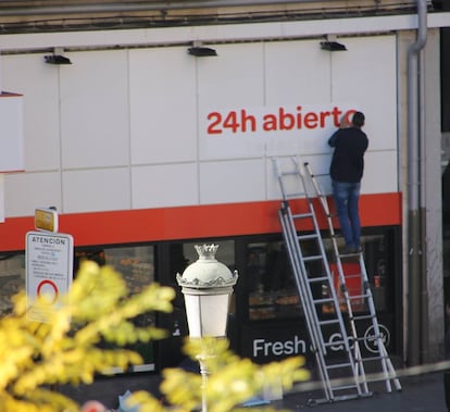 Un trabajador coloca el cartel de '24 h abierto' en el Carrefour de Lavapis, en diciembre de 2015.