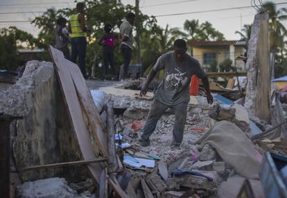 Un hombre intenta recuperar pertenencias de su casa destruida.