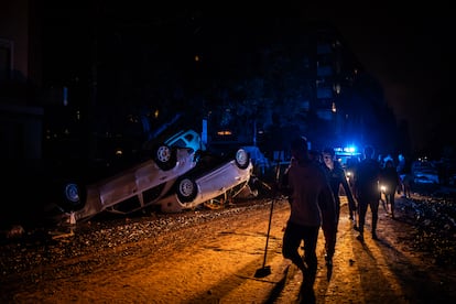 Vecinos de Paiporta caminan sobre el lodo y en la oscuridad por el centro de Paiporta, al anochecer del jueves 31 de octubre de 2024.