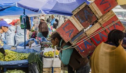 Un aparapita carga con una montaña de cajas de madera en el mercado de La Paz, en Bolivia.