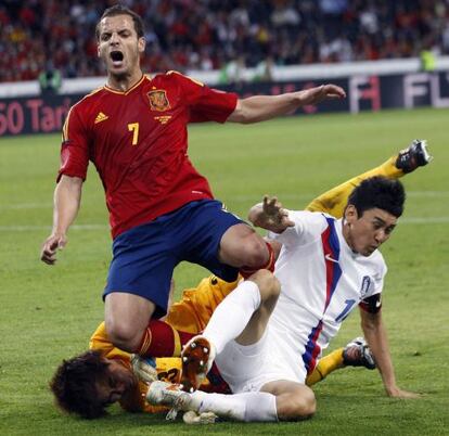 El delantero de la selección española Roberto Soldado lucha por un balón con dos jugadores de Corea del Sur.