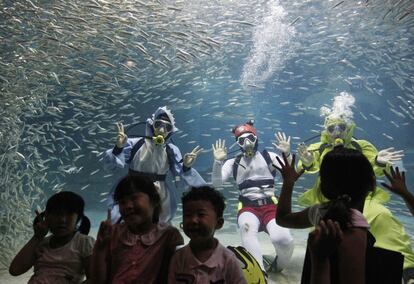 Buceadores del acuario Coex de Seúl, Corea del Sur, reciben a niños en sus instalaciones.