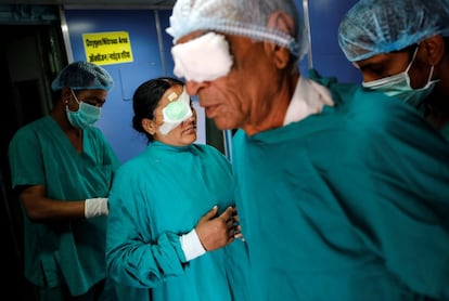 Los pacientes con los ojos vendados salen de un quirófano después de su cirugía de cataratas.
