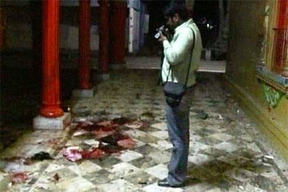 Una imagen de televisión muestra a un hombre grabando las huellas de la explosión en el templo Sankat Mochan.