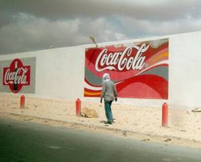 Un hombre pasa junto a una fábrica de Coca-Cola. EFE/Archivo