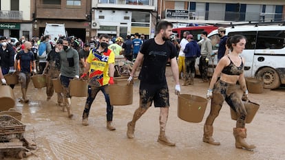 Una cadena de voluntarios retiran el lodo de las calles en Paiporta, este domingo. 