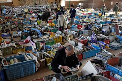 Japoneses buscan sus pertenencias entre objetos recuperados en las ruinas del terremoto. Voluntarios han dispuesto cajas con todo lo recuperado en este gimnasio de escolar de Natori.