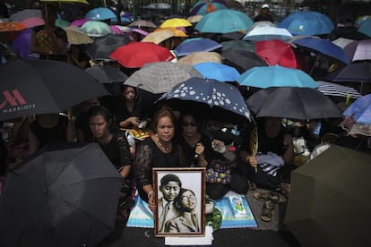 Tailandeses esperan a que pase el convoy con el féretro del rey Bhumibol de Tailandia.