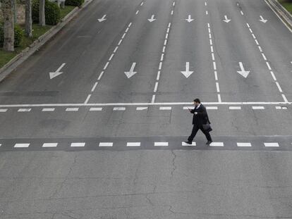 Un hombre cruza un calle vacía en Madrid.