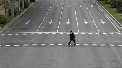 Un hombre cruza un calle vacía en Madrid.