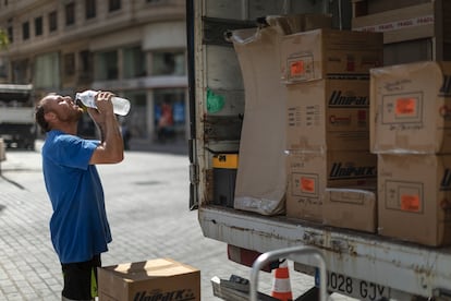Un trabajador de una empresa de mudanzas bebe agua para combatir el calor en una calle del centro de Valencia. 