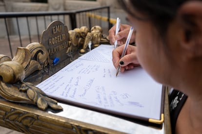 Una niña escribe un mensaje en el libro de condolencias.