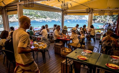 Un cambrer porta una safata amb peix fresc al xiringuito-restaurant Toc al Mar, a la cala d'Aiguablava, a Begur.