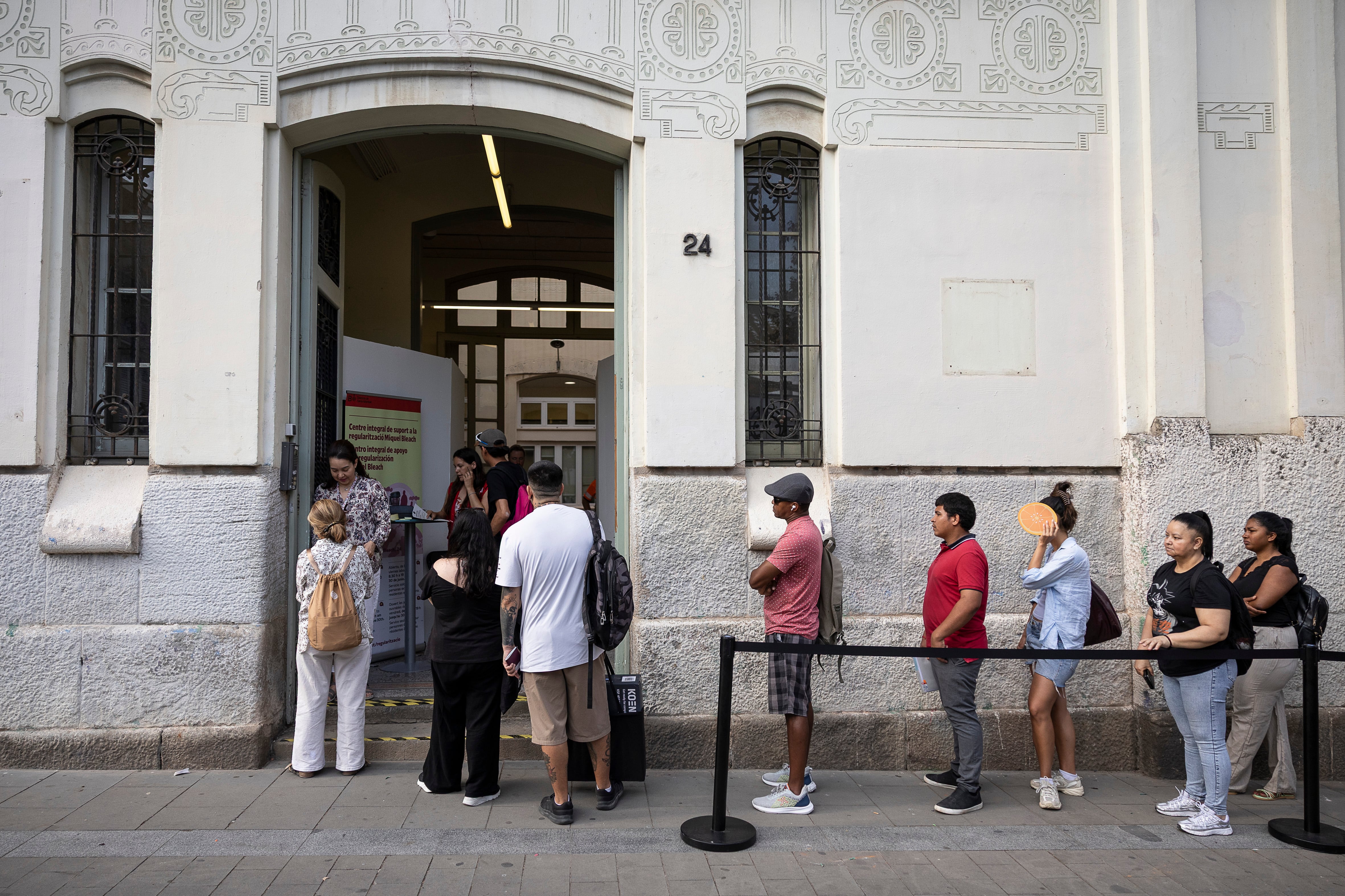 Colas para la regularización de migrantes en la oficinas del centro integral de apoyo a la regularización Miquel Bleach del Ayuntamiento de Barcelona, este lunes. 
