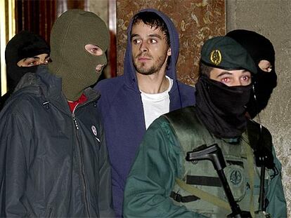 Asier Arriola (con capucha azul) sale rodeado de miembros de la Guardia Civil durante el registro anoche en un piso del barrio bilbaino de Zorroza.
