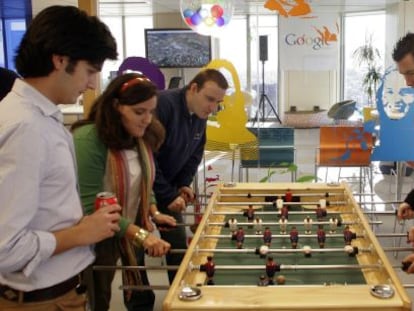 Trabajadores de Google España se relajan jugando al futbolín en la sede de la empresa durante su jornada laboral.