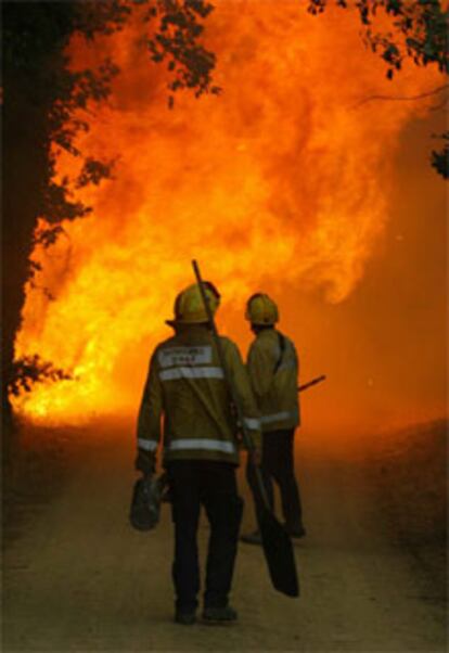 Dos bomberos contemplan las llamas en Maçanet de la Selva (Girona).