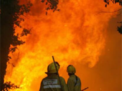 Dos bomberos contemplan las llamas en Maçanet de la Selva (Girona).