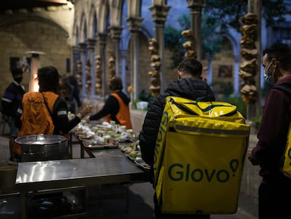 Dos repartidores de Glovo hacen cola para cenar en el comedor social de la parroquia de Santa Anna de Barcelona para celebrar el iftal, cena que rompe el ayuno diurno, este martes.