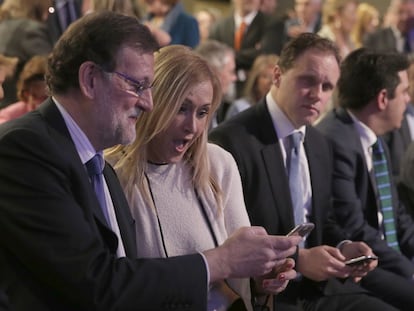 Rajoy muestra su móvil a Cifuentes, durante un acto del PP.