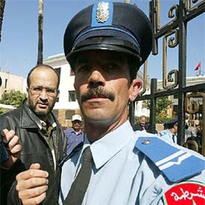 Alí Lmrabet, custodiado por un policía a la salida de su juicio en Rabat.
/ AFP