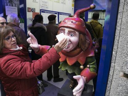 Una mujer frota su d&eacute;cimo en el Jorobado de la Suerte, una administraci&oacute;n en la calle Preciados de Madrid.