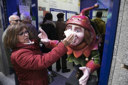 Una mujer frota su décimo en el Jorobado de la Suerte, una administración en la calle Preciados de Madrid.