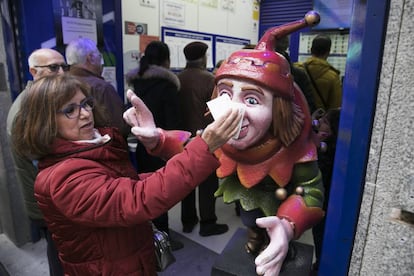 Una mujer frota su d&eacute;cimo en el Jorobado de la Suerte, una administraci&oacute;n en la calle Preciados de Madrid.