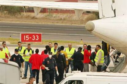 La policía española escolta a un grupo de inmigrantes que han sido enviados en avión desde Melilla a distintos centros de acogida en la Península.