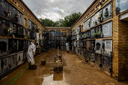 Dos voluntarios trabajan en el cementerio de Catarroja tras los daños causados por la dana.
