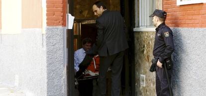 Empleados de la funeraria sacan el cuerpo de la fallecida.