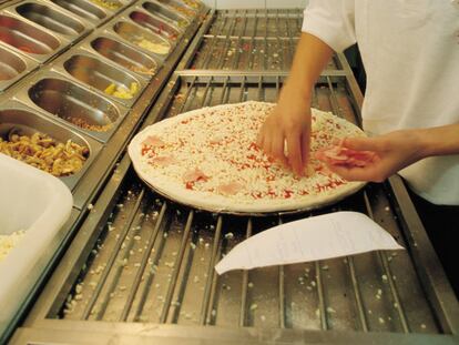 Una mujer cocina en una tienda de Telepizza.