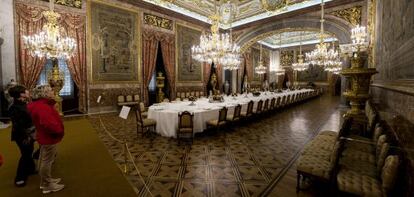 Panorámica del gran comedor para recepciones de Estado, presidido por una gran mesa y en el que también destacan las grandes lámparas de techo, del Palacio Real de Madrid.